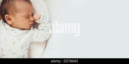 Upper view photo of a newborn baby sleeping well in bed near free space Stock Photo
