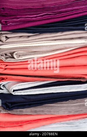 Stack of folded clean colored linens: duvet covers, sheets, pillowcases. The concept of housework and storage. Closeup Stock Photo