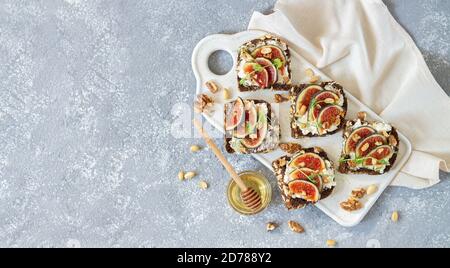 Toast with fresh figs, ricotta, nuts and honey on stone table, flat lay and copy space Stock Photo