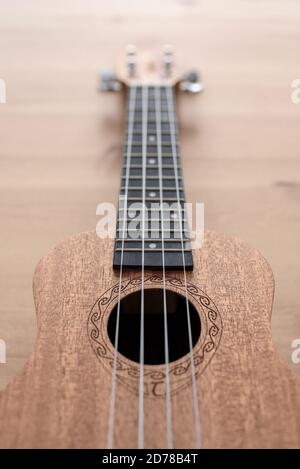 Brown ukulele on wooden background with shallow depht of field Stock Photo