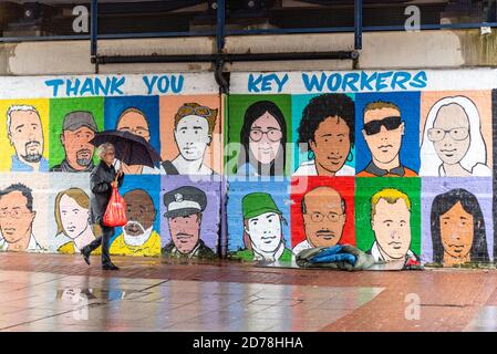 COVID 19 Key workers thank you street art with bedding of a homeless person on a wet, grim day. High Street, Southend. Raining. Person walking past Stock Photo