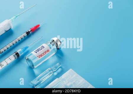A set of ampoules and syringes with the inscription Virus vaccine and a set of syringes on a blue background. Stock Photo