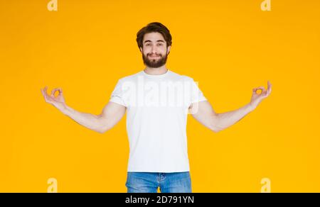 Smiling young bearded man in casual blue shirt posing isolated on yellow orange wall background. People lifestyle concept. Mock up copy space. Jumping Stock Photo
