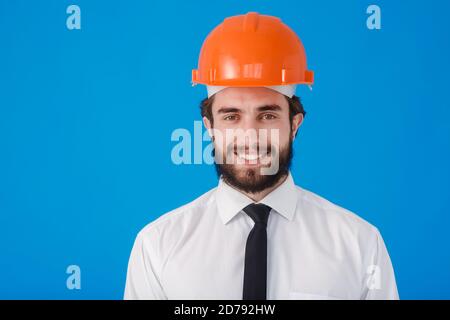 Young bearded civil engineer on blue isolated background. Studio portrait of the architect close - up Stock Photo