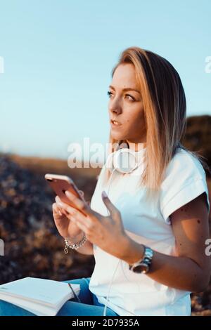 Young woman taken notes on her smartphone in the field Stock Photo