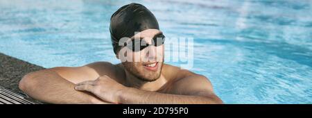 Swimmer athlete man wearing sport goggles and swim cap in indoor swimming pool portrait panoramic banner crop. Portrait of sporty active person Stock Photo