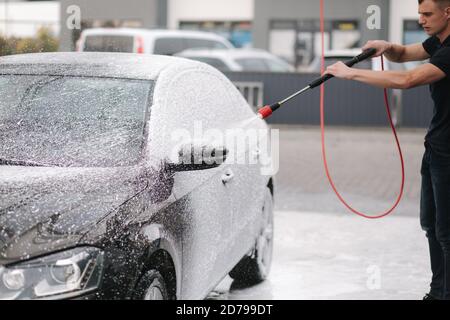 Cleaning car using active foam. Man washing his car on self car-washing Stock Photo