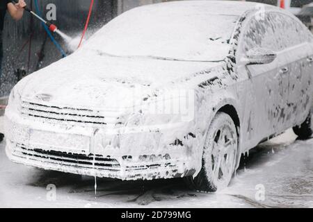 Cleaning car using active foam. Man washing his car on self car-washing Stock Photo