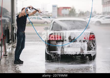 Cleaning car using active foam. Man washing his car on self car-washing Stock Photo