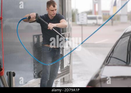 Worker cleaning car using high pressure water Stock Photo