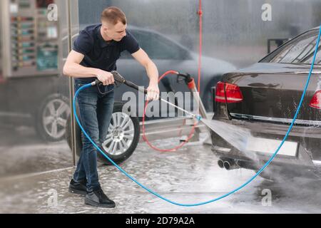Worker cleaning car using high pressure water Stock Photo