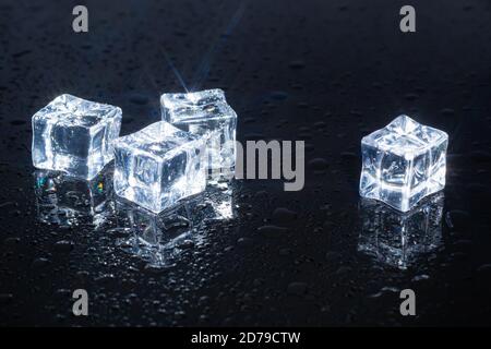 four ice cubes on black glass Stock Photo