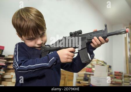 5 years little boy playing with assault rifle. Toy guns concept. Selective focus Stock Photo