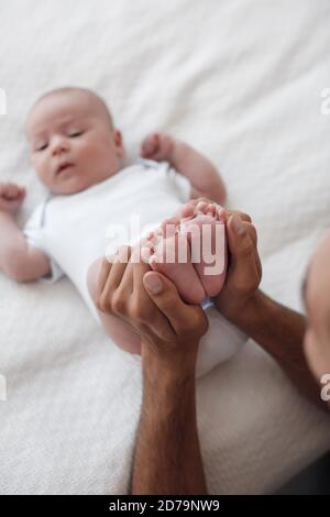 man with infant. happy family at home. happy father with cute two months baby boy laying in light bed at home