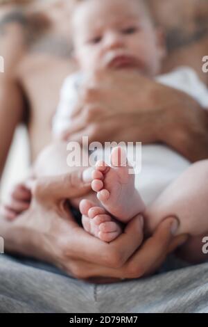 man with infant. happy family at home. happy father with cute two months baby boy laying in light bed at home Stock Photo