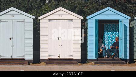 Man And Woman Couple Reading Sitting In A Beach Hut On Avon Beach Christchurch UK Stock Photo