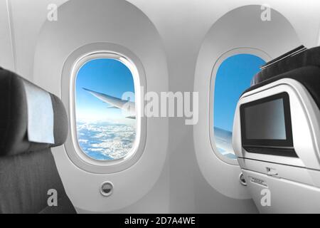 Airplane cabin seat and window view of plane wing on flight travel vacation. LCD screen display for movie entertainment while flying. Empty inside Stock Photo