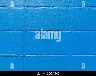 Close view of old concrete blocks painted bright blue in the early morning light. Stock Photo