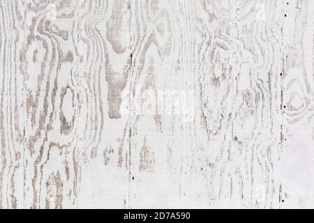 Close view of the surface of an exterior wall of plywood painted white that is faded with weather. Stock Photo