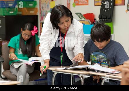Hispanic female teacher works one-on-one with a student during class at Achieve Early College High School on the campus of South Texas College. The school, part of the highly regarded McAllen school district in South Texas on the US-Mexico border, enrolls nearly 500 students, almost 3/4 of whom come from economically disadvantaged families. Stock Photo