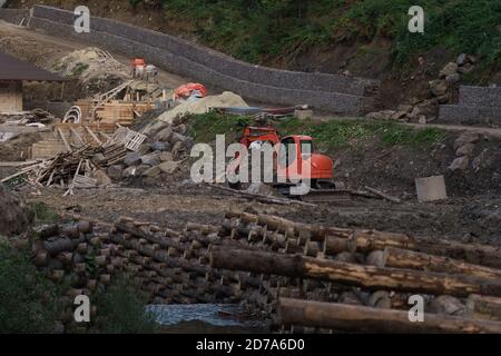 Excavator digging on construction site beside river Stock Photo