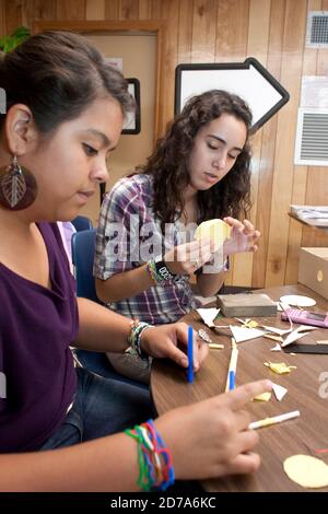 Female Hispanic students make geometric shapes out of paper during class at Achieve Early College High School on the campus of South Texas College. The school, part of the highly regarded McAllen school district in South Texas on the US-Mexico border, enrolls nearly 500 students, almost 3/4 of whom come from economically disadvantaged families. Stock Photo