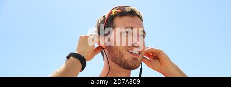 Young man putting in ear wireless bluetooth earphones wearing wearable technology. Happy person using new headphones, Stock Photo