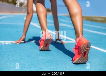 Sprinter waiting for start of race on running tracks at outdoor stadium. Sport and fitness runner woman athlete on blue run track with orange running Stock Photo