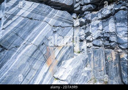 Rock cut raw surface of white and grey marble in the natural environment. Blue marble career texture. Real stone, industrial material for buildings and interior. Abstract background pattern Stock Photo