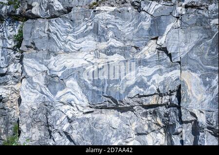 Rock cut raw surface of white and grey marble in the natural environment. Blue marble career texture. Real stone, industrial material for buildings and interior. Abstract background pattern Stock Photo
