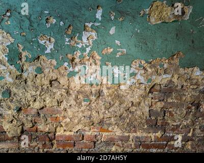 heavy damaged green painted plaster and bricks wall background and texture Stock Photo