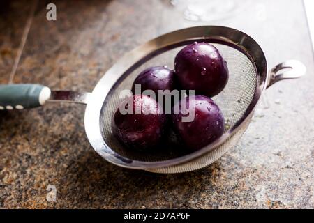 Food & Drink - Close-up of Juicy Purple Plums in a sieve Stock Photo