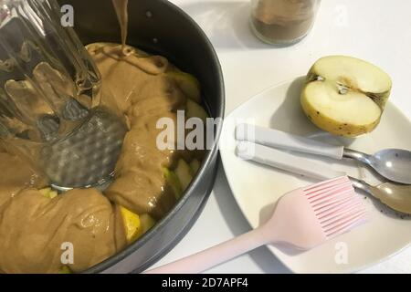 Sliced apples and dough in a baking dish. Charlotte ingredients and tools. Autumn pie with apples. Stock Photo