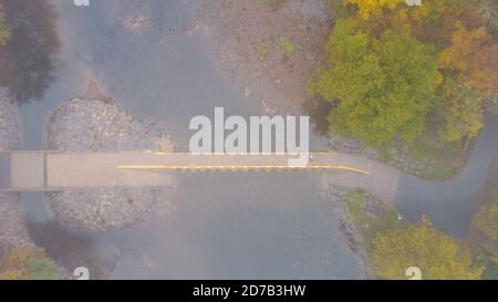 Newtown, United States. 21st Oct, 2020. A person crosses a bridge through the colorfull fall foliage during a foggy morning at the Neshaminy Creek bridge in Wednesday, October 21, 2020 at Tyler State Park in Newtown, Pennsylvania. Credit: William Thomas Cain/Alamy Live News Stock Photo