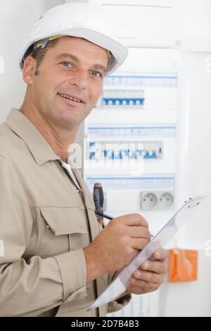 happy electrician worker checking clipboard Stock Photo