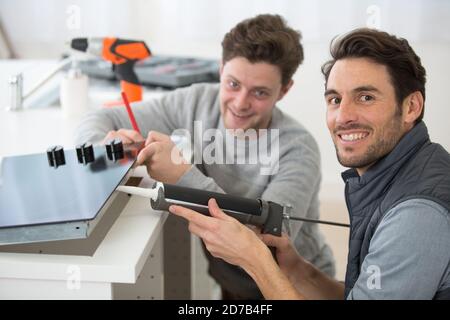 technician and apprentice using a silicon gun Stock Photo