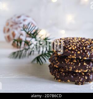 Advent and Christmas, Elisen gingerbread with chocolate glaze and hazelnut kernels, decorated on a white wooden table and a white christmas ball Stock Photo