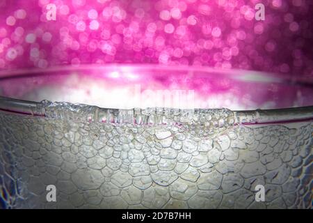 Soda Effect of Lemon Foam Pouring Out on Glass Edge on Pink Bokeh Background Stock Photo