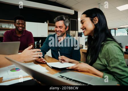 Diverse group gather to discuss work for the week sitting in office lounge before business meeting  Stock Photo