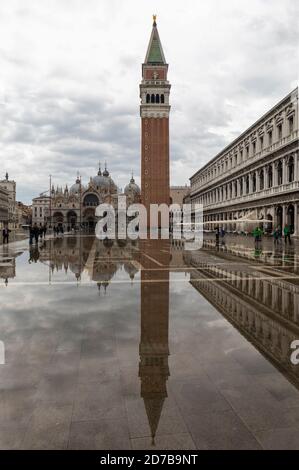High water - Acqua Alta causing flooding in Piazza San Marco. St Marks Basilica & St Marks Campanile reflected in water. St Marks Square, Venice.Italy Stock Photo