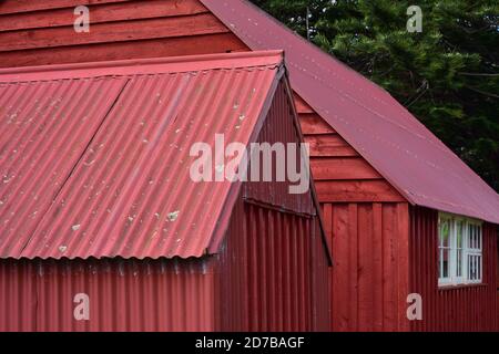 Detail view of red painted vintage sheds made from corrugated sheet metal and wood slates. Stock Photo