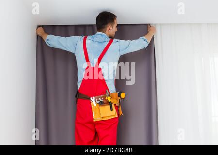 Handy man home Installation and repair service technician or home owner hanging curtains for the window treatment in a new house. Stock Photo