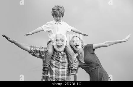 Family generation and relations concept. Concept of friendly family. Grandfather and little grandson with mother playing on blue summer sky. Stock Photo