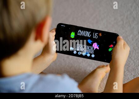 Manchester / United Kingdom - October 21, 2020: Among Us game seen on the smartphone screen and child playing it. New popular app. Stock Photo