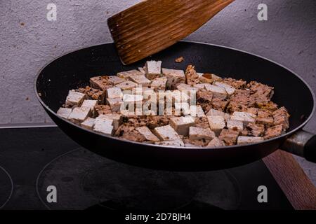 Mixing the fried tofu in the black hot pan Stock Photo