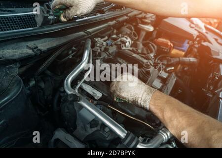 Worker repairing car and changes spark plugs in car engine in auto service, close up. Stock Photo