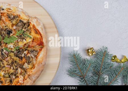 Flat lay of pizza on wooden salver, Christmas decorations around. Concept of discount and promotion in a pizzeria. Copy space, top view. Stock Photo