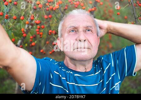 retired grandfather, makes selfie with a smartphone in the park and thinks about some important things Stock Photo