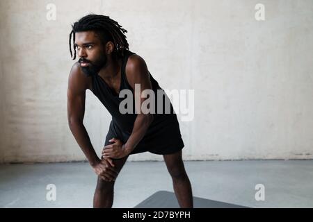 Image of young african american sportsman doing exercise while working out indoors Stock Photo