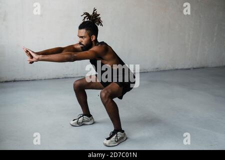 Image of young african american sportsman doing exercise while working out indoors Stock Photo